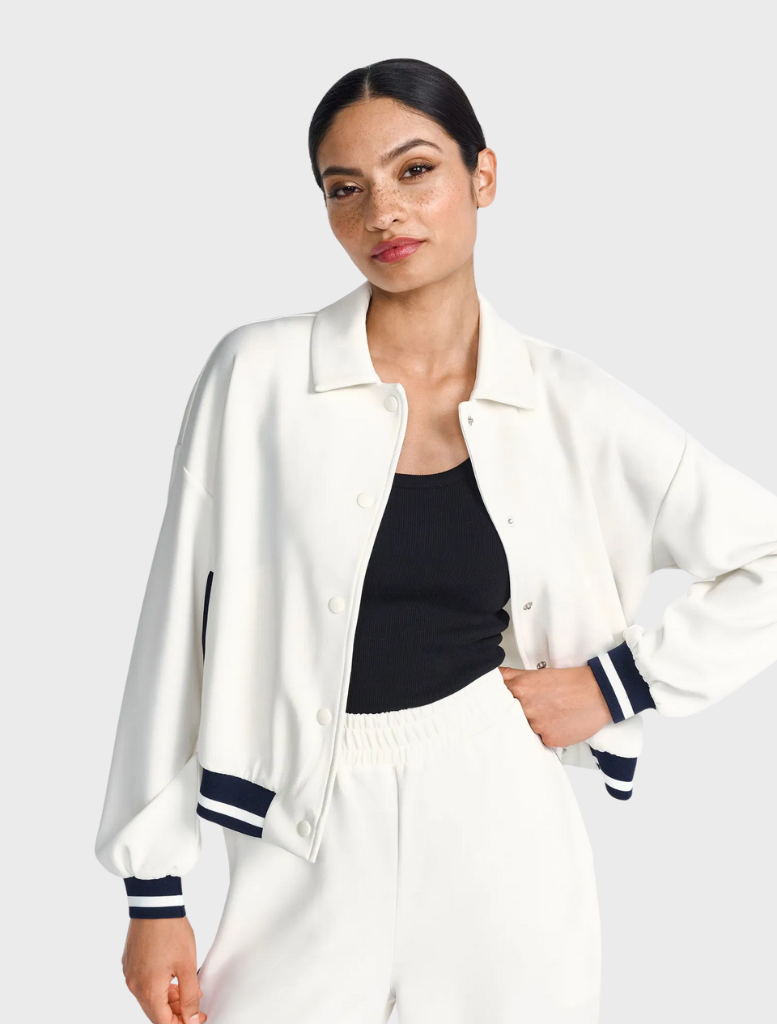A person wearing a white and navy jacket over a black top.