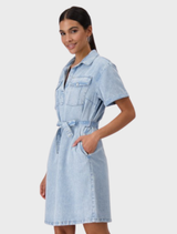 A woman models a denim shirt dress with a collar, made of lyocell, showcasing a casual yet chic look.