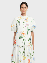 A white floral print dress paired with a white blouse and a white blazer, creating a cohesive and elegant outfit.
