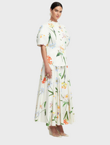 The outfit features a white floral print dress, layered with a white blouse and a stylish white blazer for a polished look.
