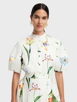 A white floral print dress is styled with a white blouse and a white blazer, presenting a fresh and elegant appearance.