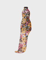 A woman in a black floral print dress, showcasing the Kiran Halter Gown with orange floral accents.