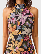 A woman models the Kiran Halter Gown, featuring an elegant black dress with a vibrant floral print.