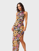 The Kiran Halter Gown in orange floral print is worn by a woman, showcasing its elegant design.