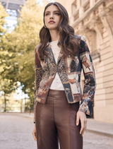 A woman models a dark brown and black knit jacket paired with leather pants, showcasing a stylish outfit.