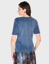 A model is dressed in a blue denim shirt and a skirt, exemplifying a chic and relaxed fashion style.