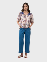 Short-sleeve top with a printed design, contrast yoke, neck bind, and decorative tucks at the yoke seams and sleeves.