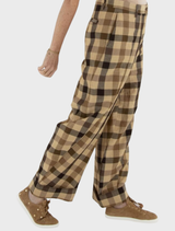 A woman models brown and black checkered trousers, showcasing a stylish and comfortable outfit.