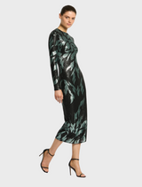 The Larissa Midi Dress in Mint Black is worn by a woman, highlighting its black fabric adorned with green leaf patterns.
