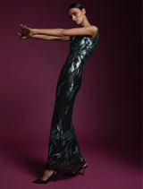 A model poses elegantly in a stylish black and green dress, showcasing a modern fashion design.