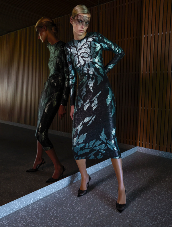 A woman wearing a black dress with a green leaf print, showcasing the Larissa Midi Dress in Mint Black.