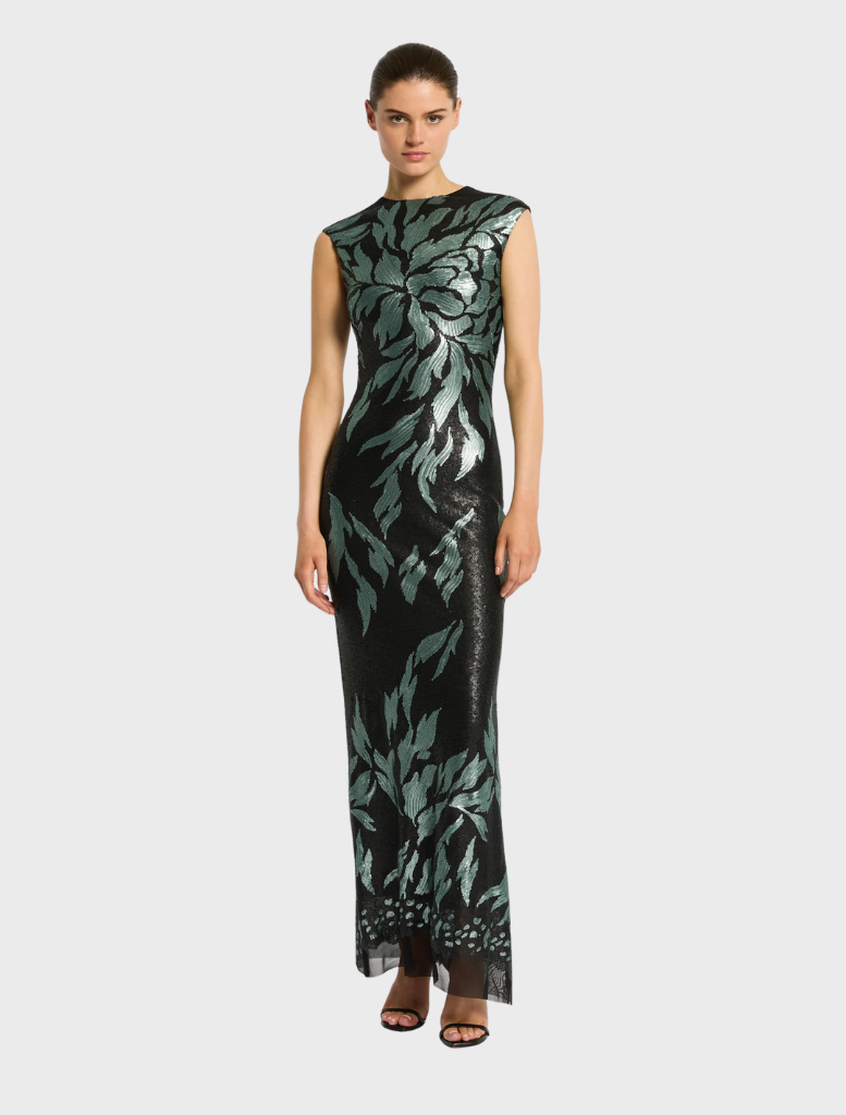 A model stands confidently in a striking black and green dress, emphasizing bold style choices.