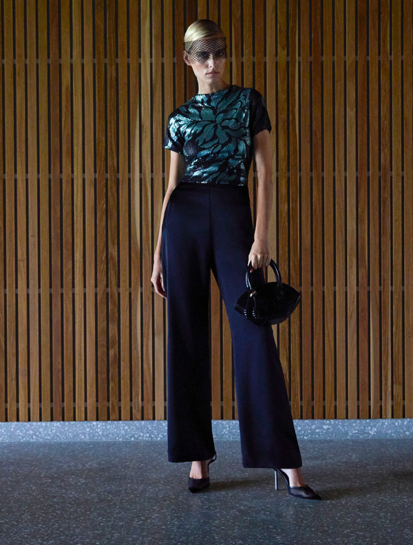 A woman wearing a black top and wide pants, showcasing the Larissa Top Mint Black style.