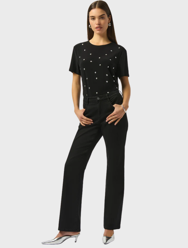  A woman wearing black pants and a matching top stands confidently, showcasing a stylish and modern outfit.