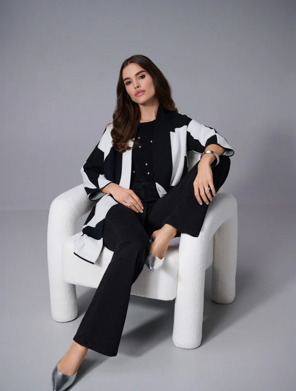 A woman dressed in black pants and a top poses elegantly, highlighting her fashionable attire.