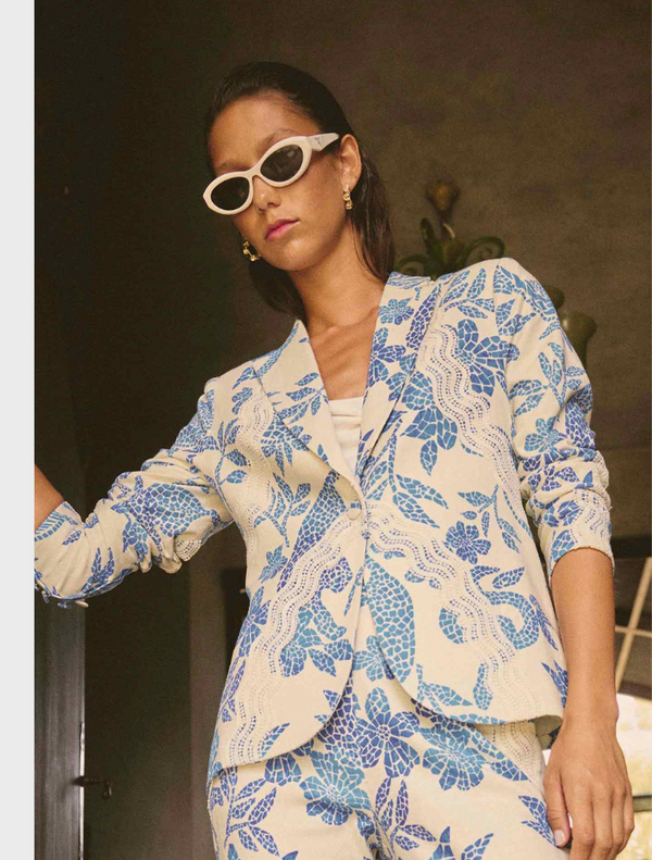 A woman wearing a blue and white floral suit, featuring the Leandro Contrast Lace Linen Viscose Stretch Blazer in Azure Mosaic.