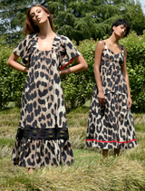 A two woman wearing a leopard print dress poses in front of trees, highlighting her fashionable choice in a natural setting.