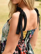 A woman showcases a floral print dress, highlighted by a cheerful design of multicolored flowers.