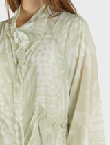 A vibrant lime print oversized nylon jacket hanging, showcasing its unique design and texture.
