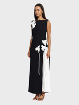 Elegant black and ivory maxi dress featuring a pleated side skirt and dimensional flower appliqués, perfect for special occasions.