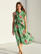 Green linen dress showcased on a hanger, emphasizing its flowing design and natural texture against a simple backdrop.