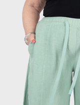 Lime linen trousers laid flat, highlighting their vibrant color and comfortable design.