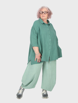 Lime-colored linen trousers displayed on a neutral background, showcasing their lightweight fabric and relaxed fit.