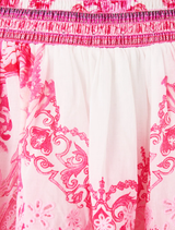 Playful mini dress in pink and white, featuring a shirred waist, adjustable straps, and a flared skirt with mosaic designs.