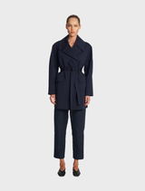 A stylish wrap trench coat in ink color, featuring a belted waist and a classic collar, perfect for layering in cooler weather.