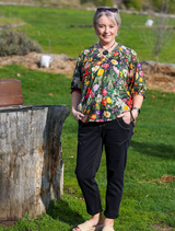Model showcases a floral blouse and wide-leg pants, featuring the Looking Glass Top in Ivy Multi design.