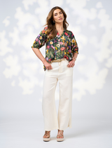 Model showcases a floral blouse and wide-leg pants, featuring the Looking Glass Top in Ivy Multi design.