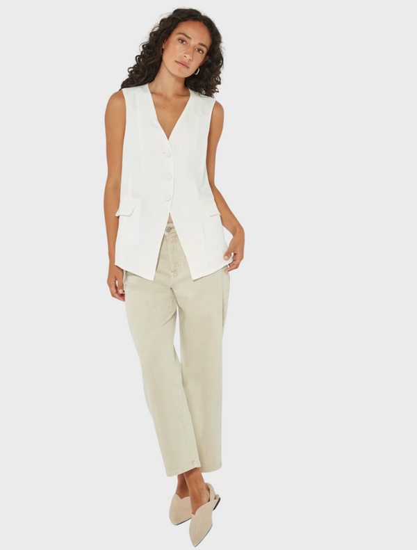 Woman wearing a stylish white sleeveless vest paired with beige trousers from Mariko Boutique