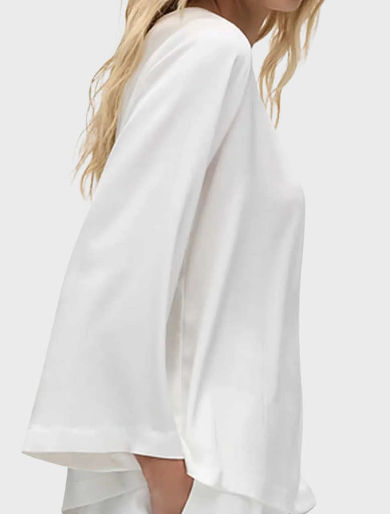 Chic ivory long-sleeve top featuring a slice neckline, combining comfort and elegance for a versatile wardrobe piece.