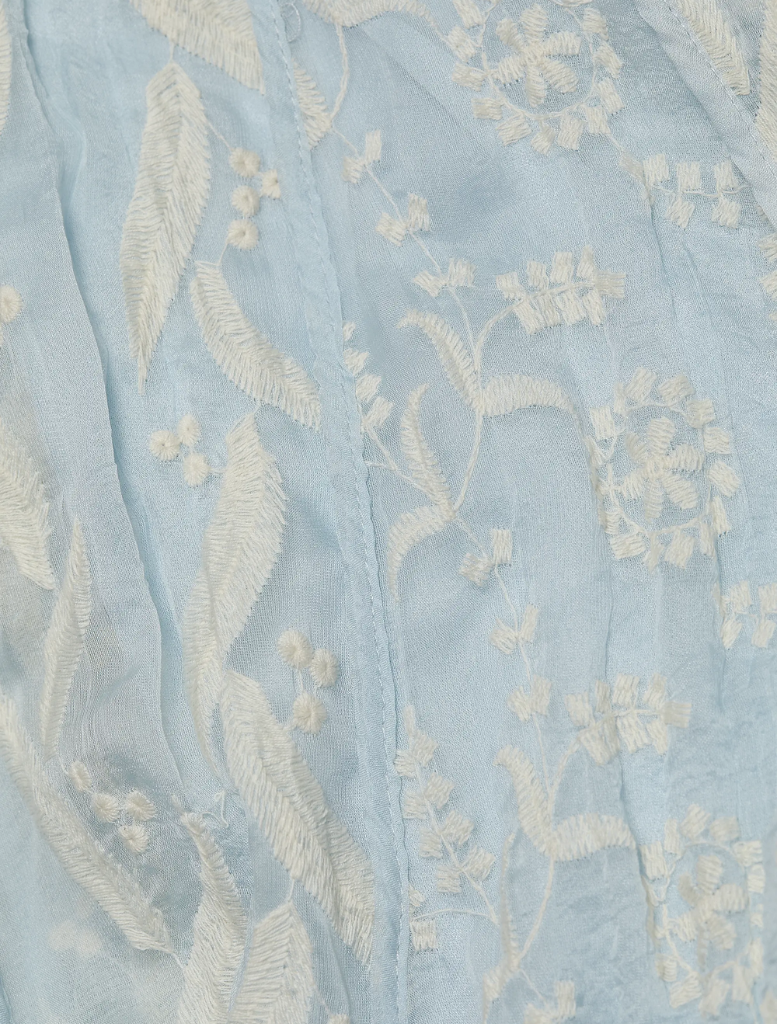 Aqua Luana Dress hanging on a rack, highlighting its vibrant color and graceful design.