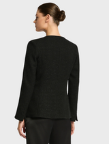 A woman in a tailored black suit paired with shorts, showcasing a modern business look.