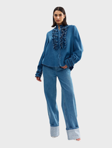 Denim Luna blouse displayed on a hanger, featuring a relaxed fit and stylish design.