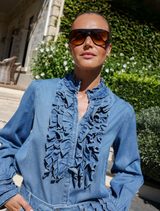 Denim Luna blouse displayed on a hanger, showcasing its stylish design and fabric texture.