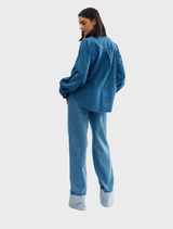 Denim Luna blouse draped on a chair, illustrating its relaxed and fashionable appearance.