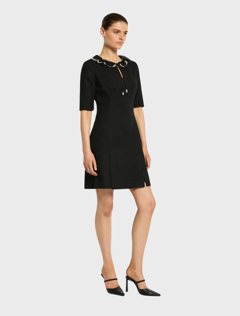 A model is dressed in a black gown with a high slit, exuding sophistication and modern style.
