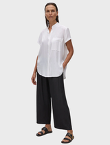 White Mache Stand Shirt displayed on a hanger, featuring a classic collar and button-down front.