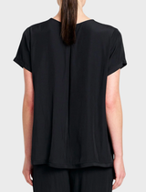 Mela Purdie's black Travel T, a lightweight tee with a scooped neckline, perfect for casual and travel outfits.