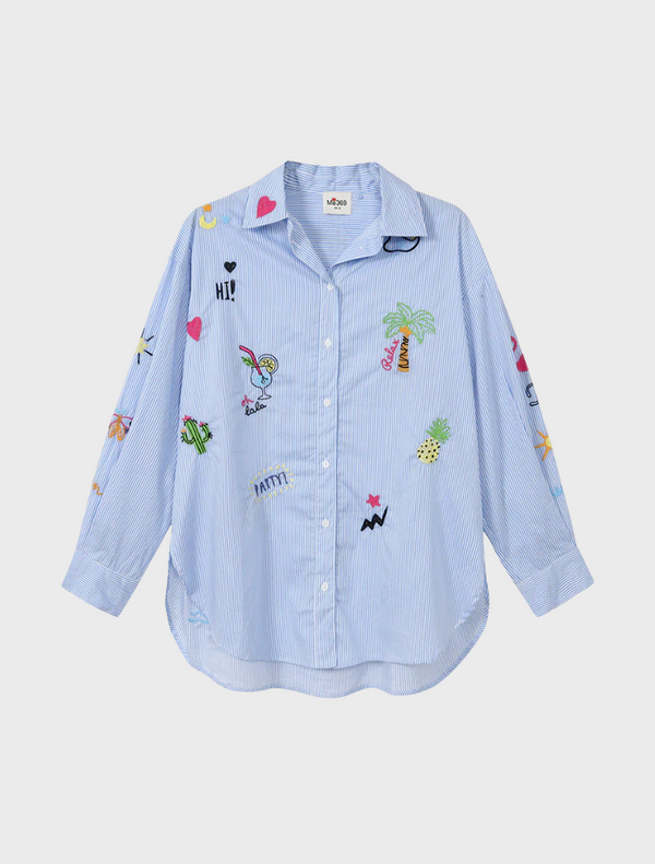 A woman dressed in a bright, patterned shirt and shorts smiles, embodying a cheerful and casual summer style.