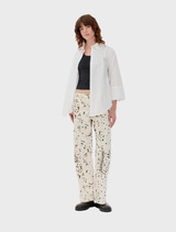 Oversized soft white shirt featuring broderie anglaise, long wide sleeves with slits, a collar, and front button closure.