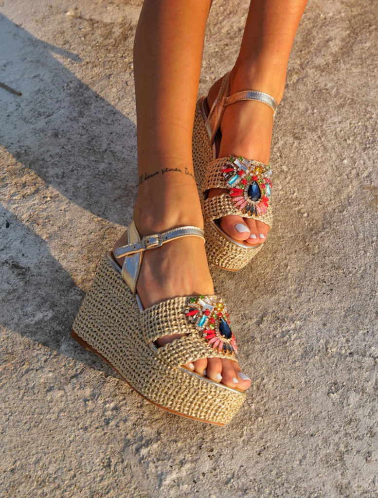 A woman in a vibrant red dress and sandals stands on steps, exuding elegance and confidence.