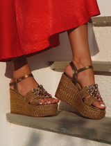 A woman wearing a red dress and sandals poses on steps, showcasing her stylish outfit.