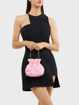 A woman in a black dress holds a pink Mattie Sequin Pouch purse, showcasing a stylish and elegant look.