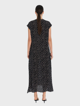 A woman is dressed in a black polka dot maxi dress, referred to as the Maxi Slice Dress - Black/Meringue.