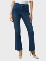 A woman dressed in a white shirt and medium blue jeans poses, highlighting a timeless and stylish outfit choice.