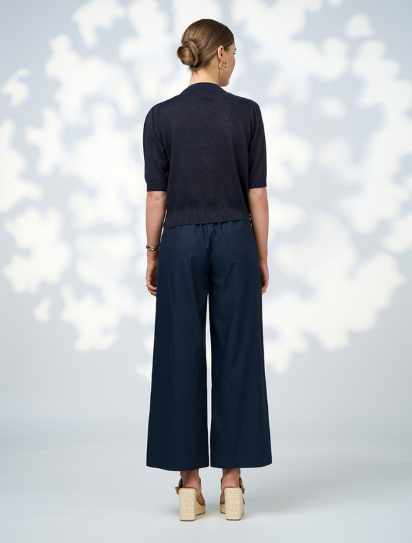 The model is dressed in a navy cardigan and wide-leg pants, presenting a chic and comfortable fashion ensemble.
