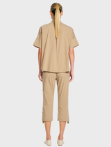 The Tab Shell showcases a rouleau loop and button neck closure, crafted from lightweight, stretch cotton-blend fabric.